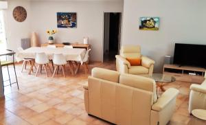 un salon avec une table, des chaises et une télévision dans l'établissement Aux Cyprès du Sud : mer et montagne, à Logrian-et-Comiac-de-Florian