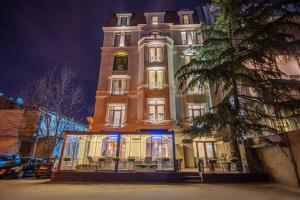 un edificio alto con una torre iluminada por la noche en City Avenue Hotel, en Tiflis