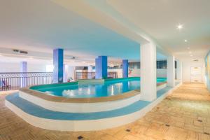 a large swimming pool in a building with blue columns at Mirachoro Carvoeiro in Carvoeiro