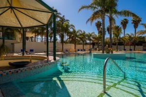 a large swimming pool with palm trees and an umbrella at Mirachoro Carvoeiro in Carvoeiro