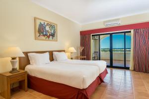 a bedroom with a large bed and a balcony at Mirachoro Carvoeiro in Carvoeiro
