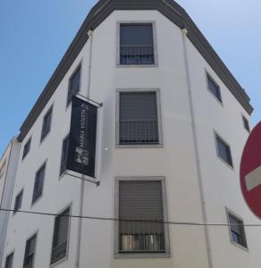 un edificio blanco con ventanas y un cartel en él en Maria Violeta Tourism Apartment, en Cadaval