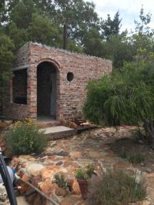 a brick building with a door in a garden at BARE NECESSITIES, NUDIST ONLY VENUE Naturist, clothes free in Swellendam