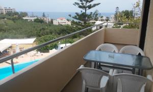 balcón con mesa, sillas y piscina en Alexandros Studios, en Kalamaki