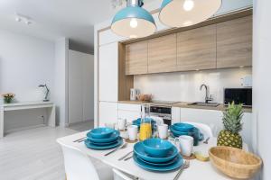 uma cozinha com uma mesa branca com pratos azuis em Elite Apartments Downtown Premium em Gdansk