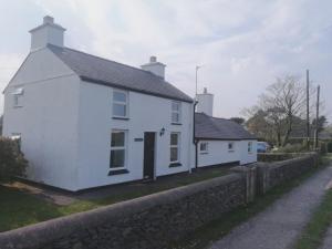 a white house sitting next to a stone wall at Gors Eilian in Amlwch