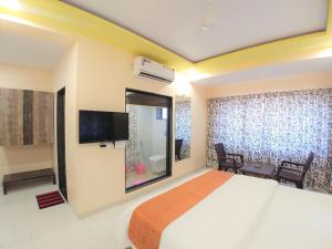 ein Hotelzimmer mit einem Bett und einem Flachbild-TV in der Unterkunft Hotel Mangal Residency Lonavala - Best Hotel in Lonavala in Lonavla