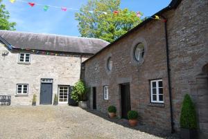 un viejo edificio de ladrillo con una bandera. en Glanhenwye Courtyard Cottages en Glasbury