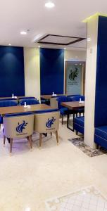 a restaurant with blue walls and tables and blue chairs at Swiss Blue Al Samer in Jeddah