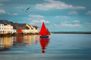 een boot met een rood zeil in het water bij The Herons Rest Townhouse B&B in Galway
