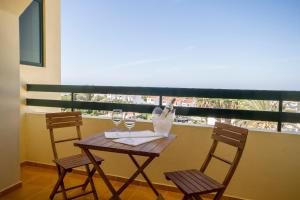 a table with two chairs and wine glasses on a balcony at Mirachoro Carvoeiro in Carvoeiro