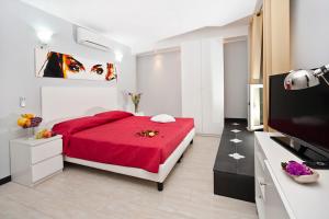 - une chambre avec un lit rouge et une télévision à écran plat dans l'établissement Locanda Paradiso, à Gênes