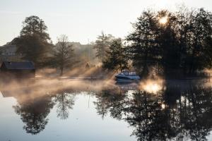 a boat on a lake with fog on the water at Hotel Ry in Ry