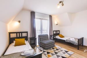 a bedroom with two beds and a chair and a window at Apartamenty GÓRKA in Białka Tatrzańska