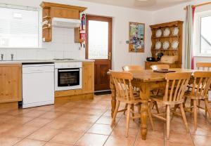 a kitchen with a wooden table and chairs in it at Ballybunion Holiday Cottages No 7 in Ballybunion