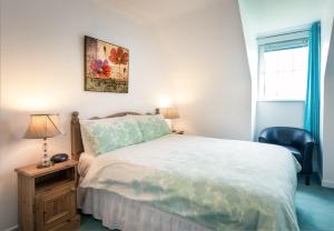 a bedroom with a bed and a chair and a window at Ballybunion Holiday Cottages No 7 in Ballybunion