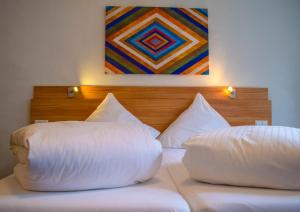 two white pillows on a bed with a painting on the wall at Hotel Capri in Überlingen