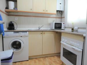 a kitchen with a washing machine and a microwave at Lamoga-Sandi 4 2 in Torredembarra