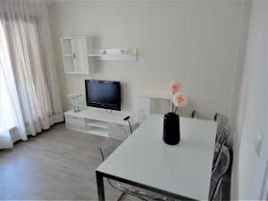 ein weißes Wohnzimmer mit einem Tisch und einem TV in der Unterkunft Lamoga-Sandi 4 2 in Torredembarra