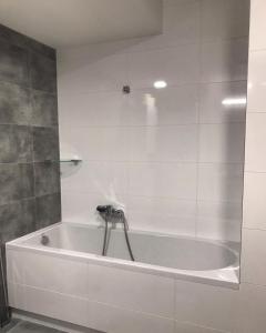 uma banheira na casa de banho com azulejos brancos em Apartmán T5 Vrchlabí em Vrchlabí