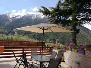 ein Tisch und Stühle unter einem Sonnenschirm auf einer Terrasse in der Unterkunft Rue de Vachery 46 in Etroubles