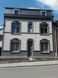 a white house with three windows and a door at Hébergement Les Heros in Liège