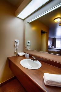 a bathroom with a sink and a large mirror at Motel Invitation in Sainte-Marie