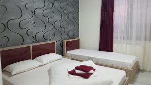 Dos camas en una habitación con toallas rojas encima. en Vila Fara Nume, en Mamaia Nord – Năvodari