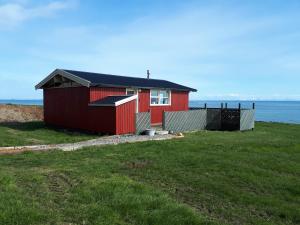 a red house on the side of a beach at Skjaldvararfoss sumarhús in Múli