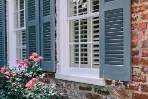 two windows with green shutters on a brick building with flowers at Zero George Hotel in Charleston