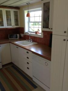 cocina con armarios blancos, fregadero y ventana en Gîte Au Blanc Marronnier, en Racine