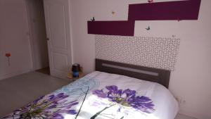 Un dormitorio con una cama con flores púrpuras. en Gite pour 6 ou chambre pour 2 à FORMIGNY, en Formigny