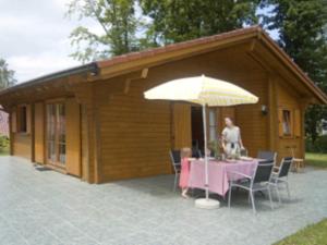 Eine Frau, die an einem Tisch unter einem Schirm sitzt. in der Unterkunft Ferienhaus - Weißer Steg Sieben in Ostseebad Sellin
