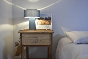 una mesita de noche con una lámpara junto a una cama en Appartement d'Hôtes Temps de Pause, en Lautrec