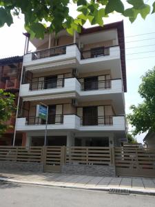 ein hohes weißes Gebäude mit Balkonen auf einer Straße in der Unterkunft Dimitra's Apartments in Olympiakí Aktí