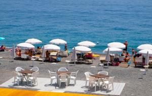 a beach with chairs and tables and white umbrellas at Casa degli Oleandri in Roccalumera