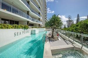a swimming pool in front of a building at Sea Pearl A1 Beach Resort in Mooloolaba