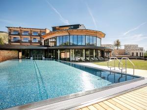 a house with a swimming pool in front of a building at Almwellness Hotel Pierer in Fladnitz an der Teichalm