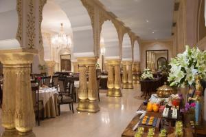a dining room with tables and chairs and a chandelier at Jai Mahal Palace in Jaipur