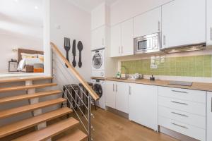 een keuken met witte kasten en een trap in een kamer bij With You Suites in Lissabon