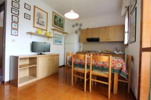a kitchen with a table and chairs and a television at Appartamenti Valbella con piscina in Bibione