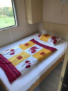 a bed in a small room with a quilt on it at Mobilheim am Wald in Bernau bei Berlin
