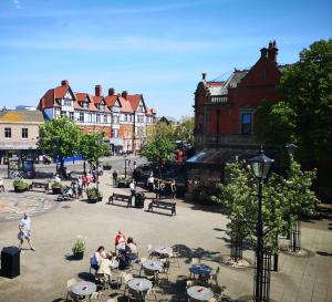 Eine Gruppe von Menschen sitzt an Tischen in einem Innenhof in der Unterkunft Mode Hotel Lytham in Lytham St Annes