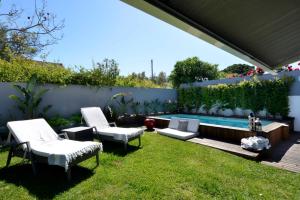 un patio trasero con 2 sillas y una piscina en Estoril Garden Villa - 4Bedroom private pool - CheckinHome en Alcabideche