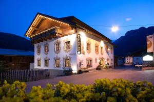 Un grand bâtiment blanc avec des lumières allumées la nuit dans l'établissement B&B Wienerhof, à Trins