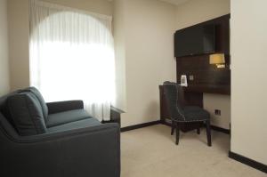 a living room with a couch and a chair and a television at Great Victoria Hotel in Bradford