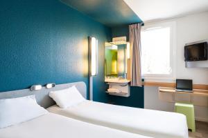 a bedroom with two beds and a blue wall at ibis budget Paris Porte de Vincennes in Paris