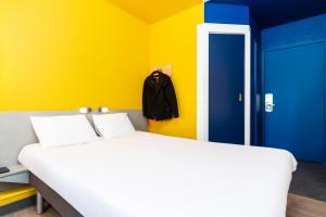 a bedroom with a white bed and a blue and yellow wall at ibis budget Paris Porte de Vincennes in Paris