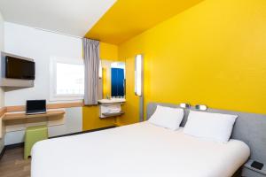 a hotel room with a bed and a yellow wall at ibis budget Paris Porte de Vincennes in Paris