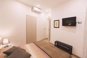 una camera da letto con un letto e una TV a parete di Residenza Macos a Siracusa Altre 7 foto